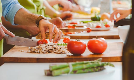 People taking part in a cooking class slicing vegetables
