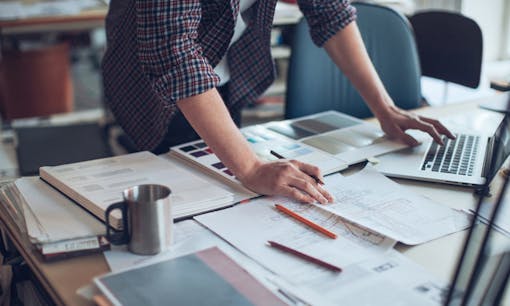 Person working at a computer desk filled with papers