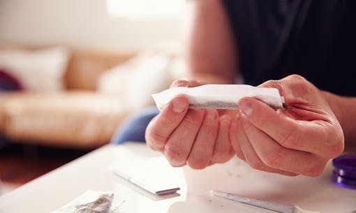 A man rolling a joint in his living room