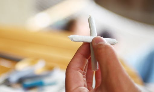 Man holding cannabis cross joint