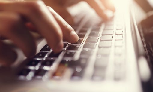 Person typing on laptop keyboard