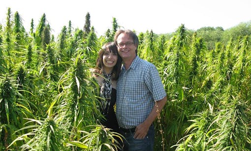 Jodie and Marc Emery stand together in an outdoor cannabis field