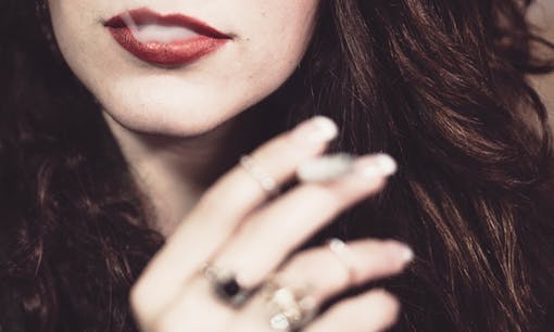 Woman holding cannabis joint and while smoke emits after she inhales