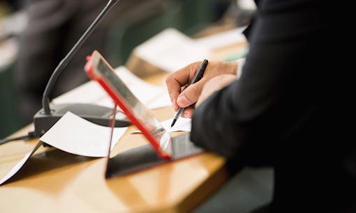 A businessman taking notes on a tablet during a conference
