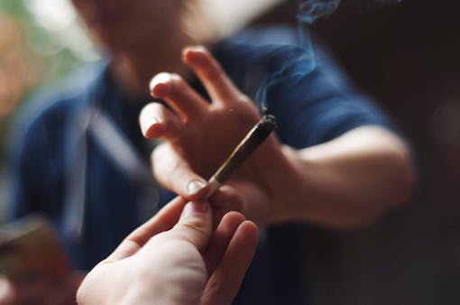 Two friends passing cannabis joint outside
