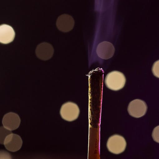 Cannabis joint in moody lighting with purple bokeh effects in the background