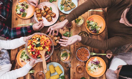 Friends eating at large table of food