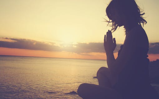 Woman meditating on the beach