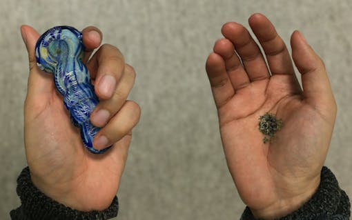 Holding a pipe in one hand and some cannabis in the other hand