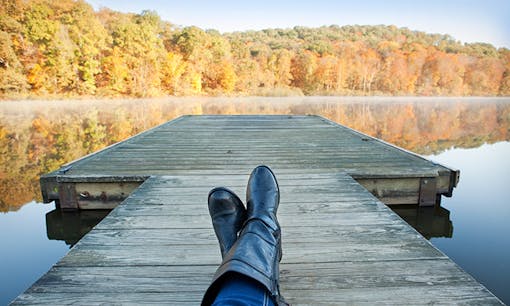 Person relaxing on lakeside dock in autumn