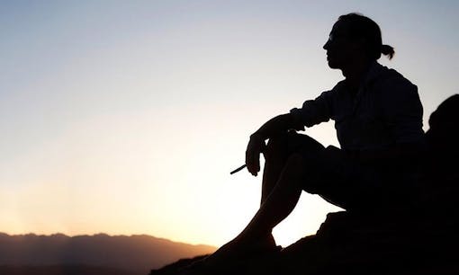 Silhouette man smoking joint at sunset looking out at nature