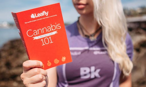 A blonde woman holding the Leafly Cannabis 101 pamphlet