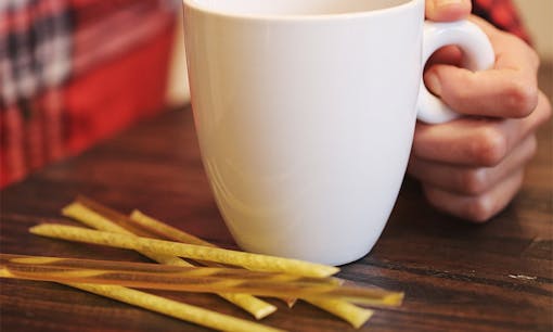 IRIE CBD cannabis honey sticks next to a coffee mug on a wood table