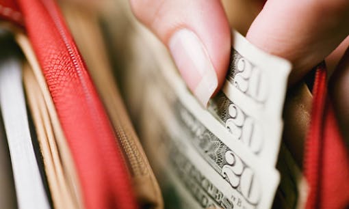 Woman grabbing US paper currency from her wallet