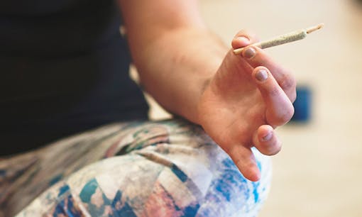 Woman holding annabis joint while doing yoga