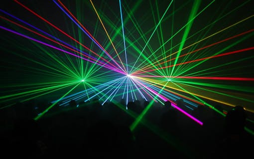silhouetted people watching a fullcolor laser beam-show