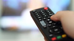 Television remote changes channels on a screen. (AdobeStock)