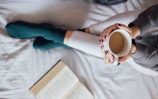 Woman on the bed with book and coffee