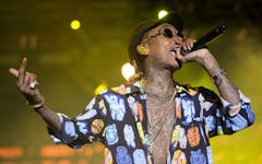 photo of Wiz Khalifa performing with a microphone in his hand on stage