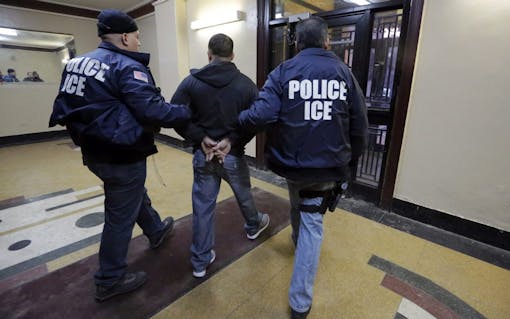 In this March 3, 2015 photo, Immigration and Customs Enforcement officers escort an arrestee in an apartment building, in the Bronx borough of New York, during a series of early-morning raids. Immigrant and Customs Enforcement say an increasing number of cities and counties across the United States are limiting cooperation with the agency and putting its officers in dangerous situations as they track down foreign-born criminals. Instead, more of its force is out on the streets, eating up resources and conducting investigations because cities like New York and states like California have passed legislation that limits many of the detention requests issued by immigration authorities. (AP Photo/Richard Drew)