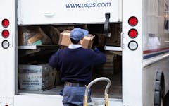 postal delivery man in back of open truck