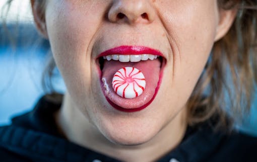 sublingual vs edibles dosing; woman holding candy on tongue