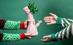 Arms wearing Christmas sweaters holding a wrapped bong