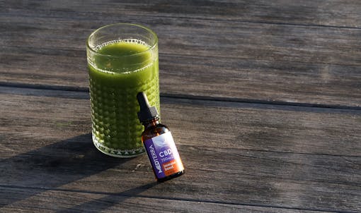 Medterra CBD outdoors leaning on glass of green juice