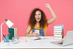 Happy student in front of a desk, pumping her fist