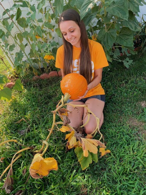 Woman kneeling on grass with her pumpkin