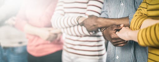 People of multiple skintones holding hands in a line