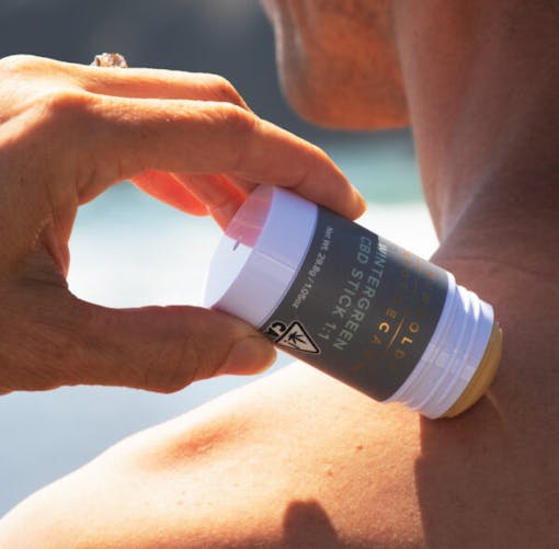 A woman applies a roll-on pain topical to her neck in this lifestyle photo for Humboldt Apothecary. (Courtesy Humboldt Apothecary)
