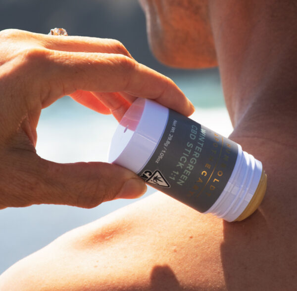 A woman applies a roll-on pain topical to her neck in this lifestyle photo for Humboldt Apothecary. (Courtesy Humboldt Apothecary)