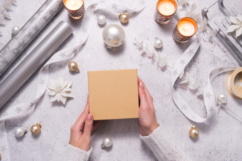 A woman is holding a gift box between silvery and white jewelry. Preparing for Christmas and New Years Eve.