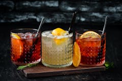 multi colored cocktails on a dark background with fruit slices and stylish glasses