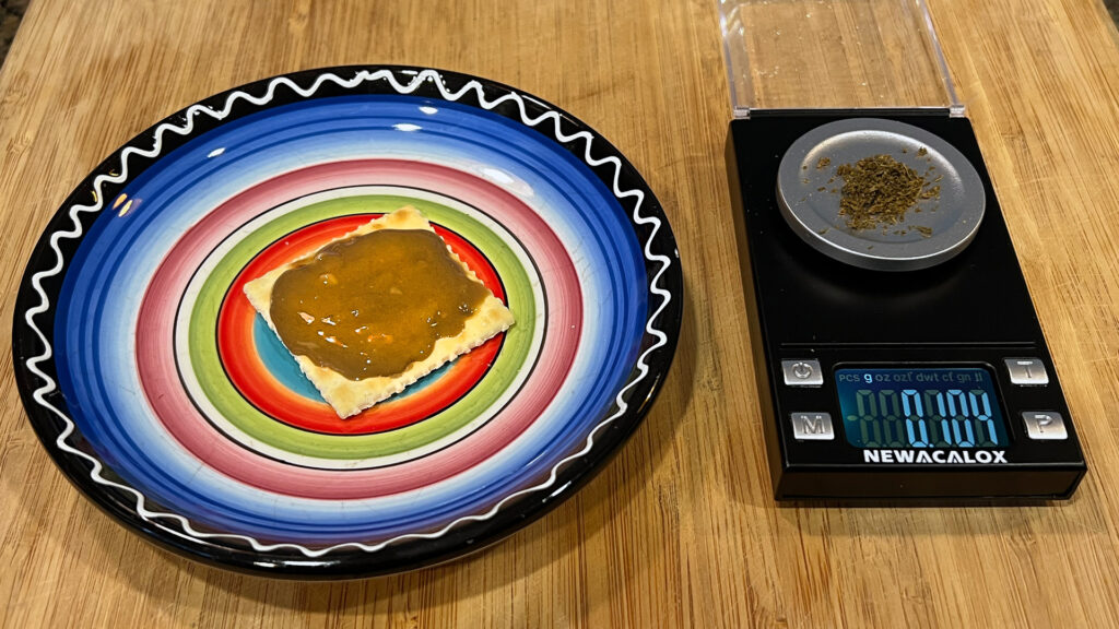 Cannabis cracker on a brightly colored plate next to a 0.104 gram scale