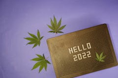 Hello 2022 on message board. Cannabis leaf flat lay. New Year