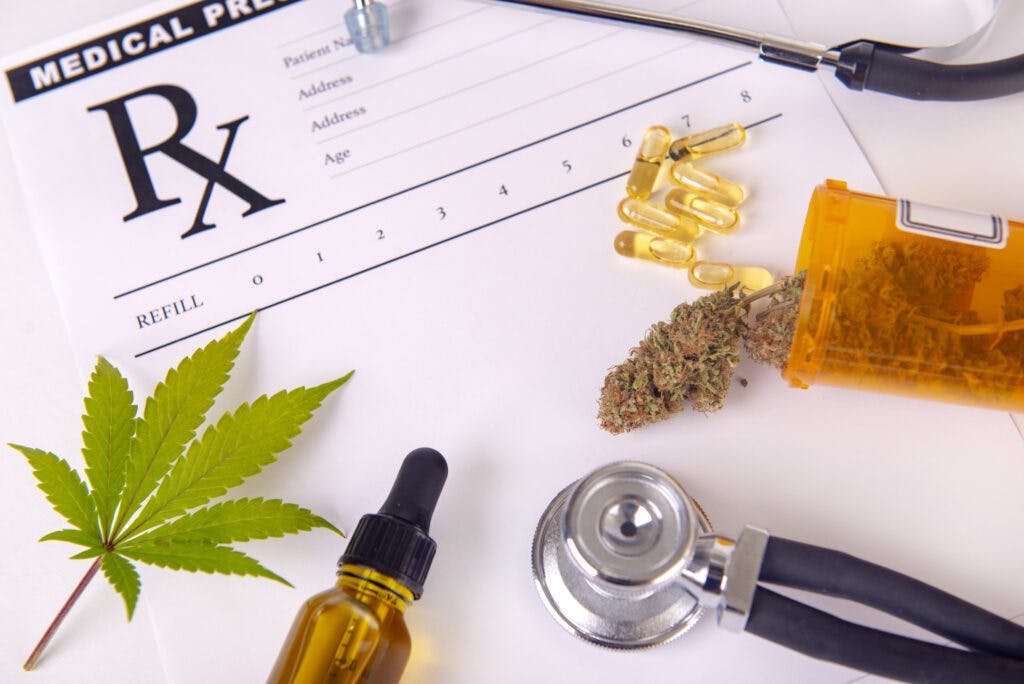 Various cannabis products, pills and CBD oil over medical prescription sheet - medical marijuana concept