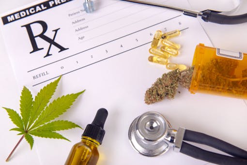 Assorted cannabis products, pills and cbd oil over medical prescription sheet - medical marijuana concept