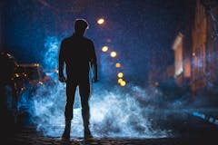 The man smoke in the cloud of smoke. Evening night time. Telephoto lens shot