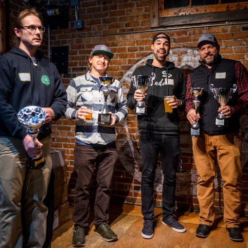 Four Lovers Cup winners smile on stage with their trophies at Draught Works Brewery in Missoula