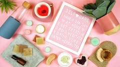 Self-care wellbeing home spa letterboard with herbal hibiscus tea, pro environmental plastic free beauty products and moisturisers on feminine pink background.