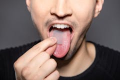 man takes breath stripes on his tounge that refreshes breath in mouth, removes smell and kills bacteria and germs