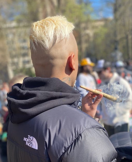 A man with blonde hair smokes a jumbo joint in New York City.