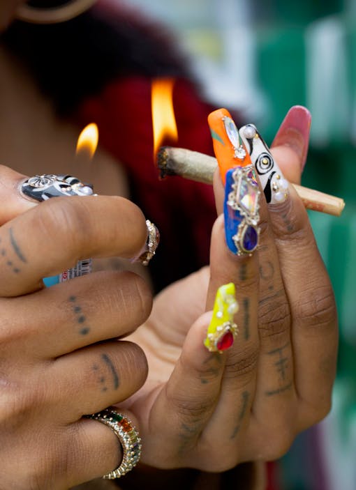 A woman with decorated fingernails lights a joint in New York's Washington Square Park.
