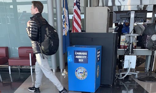 a man walks past a blue amnesty box next to TSA screening area