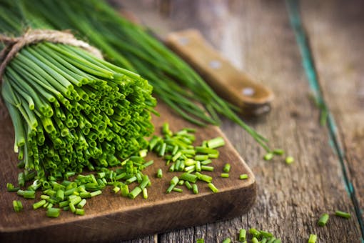 bunch of fresh chives on a wooden cutting board, selective focus