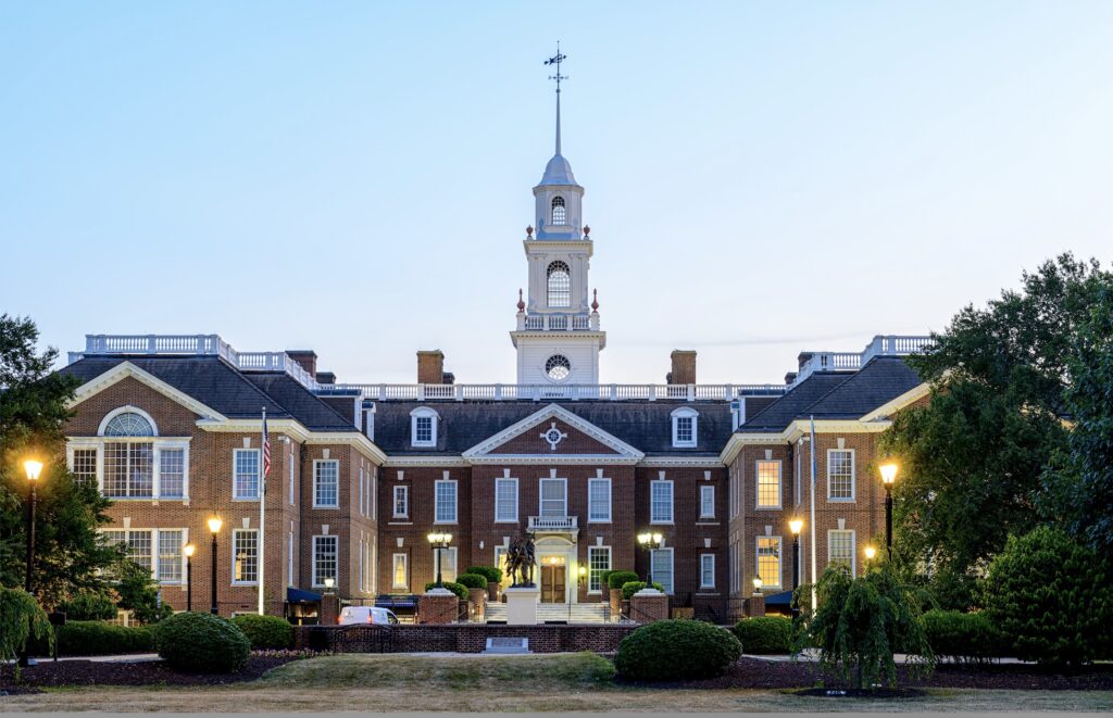 External photo of the brick Delaware Capitol Building lit by elegant lampposts at sunset