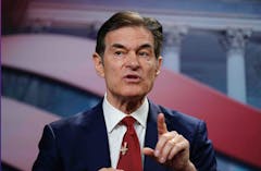 man in suit and red tie gesticulates with raised finger