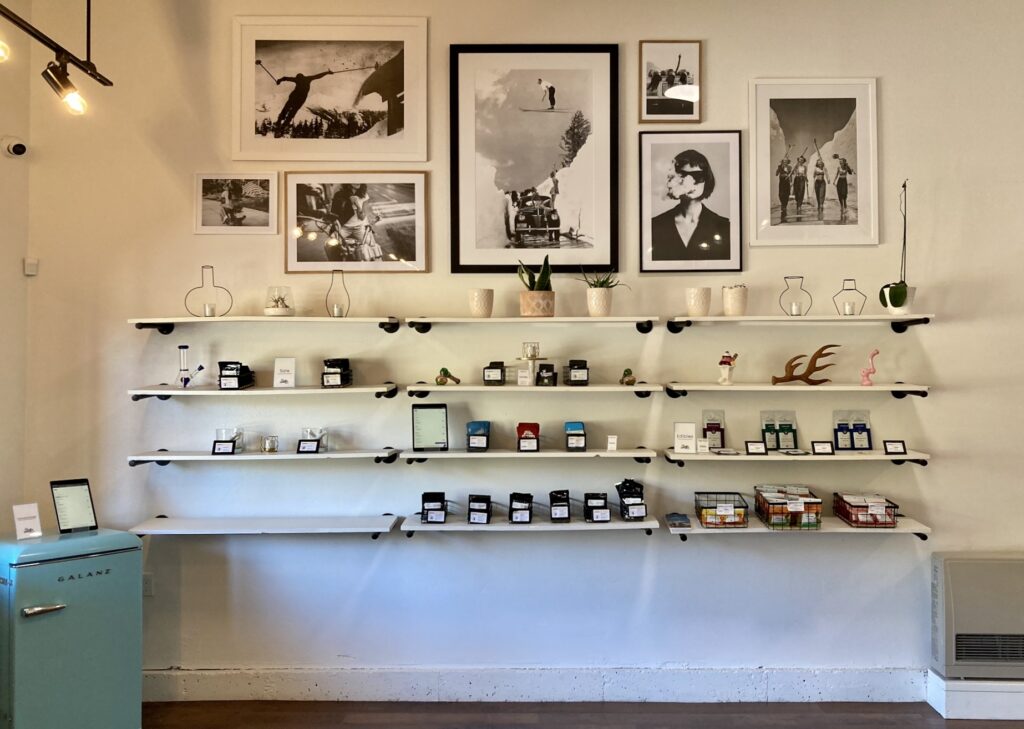 Cannabis products on shelves against white wall, with framed posters and photographs above